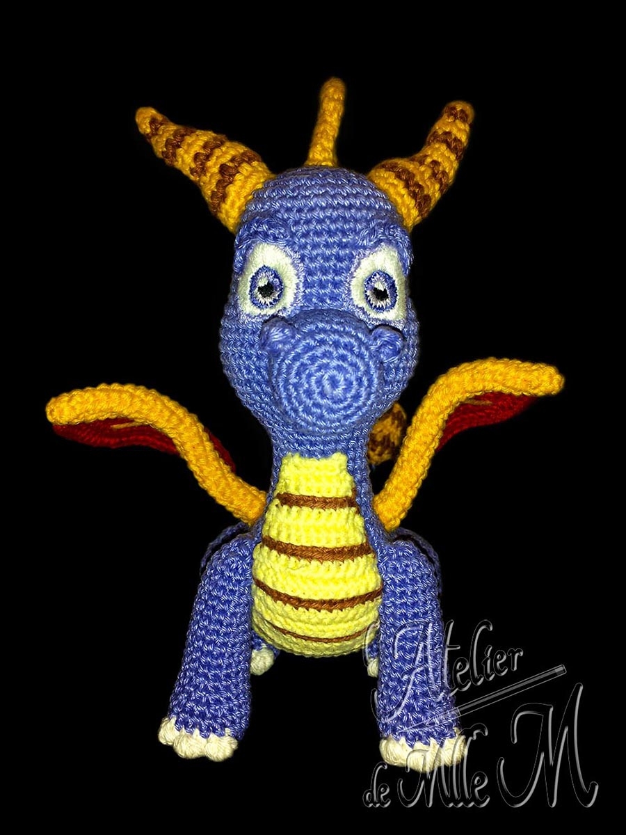 Dragon Spyro. Une représentation assez fidèle du dragon du célèbre jeu vidéo. Composition : Fil 100% coton et rembourrage polyester. Yeux brodés en coton mouliné. Dimensions : 19 x 15 x 18 cm.