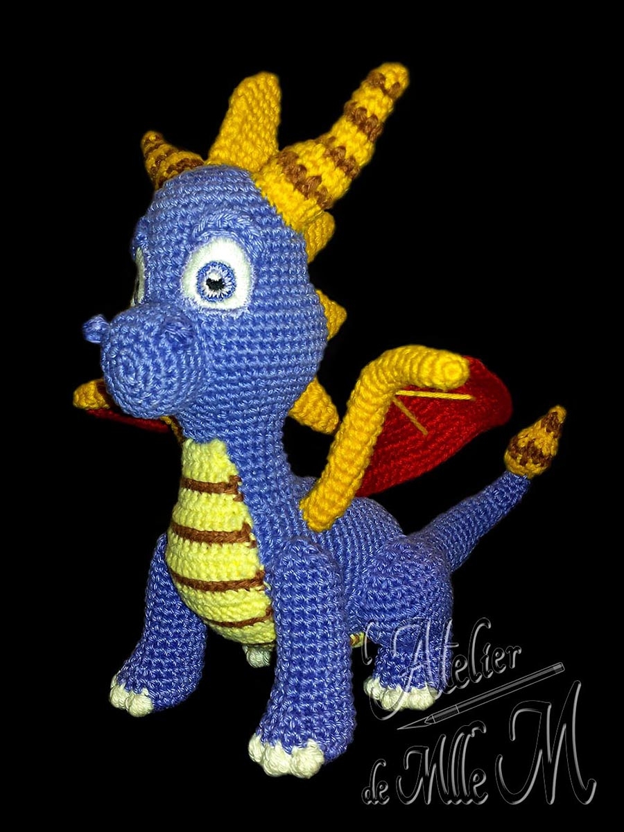 Dragon Spyro. Une représentation assez fidèle du dragon du célèbre jeu vidéo. Composition : Fil 100% coton et rembourrage polyester. Yeux brodés en coton mouliné. Dimensions : 19 x 15 x 18 cm.