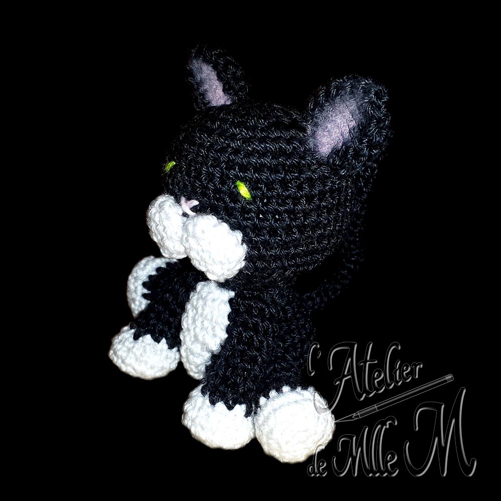 Minou Choo. Un petit chat noir aux chaussettes blanches. Création appartenant à la gamme des "Amis Choo". Composition : Fil 100% coton et rembourrage polyester.