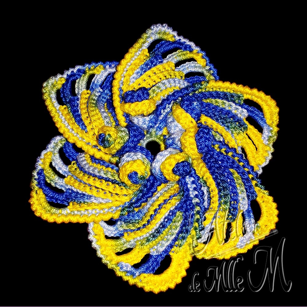 Une fleur à 6 pétales bleues et jaunes réalisée au crochet ; à monter en barrette, en broche, ou à utiliser en déco. Composition : Coton perlé N°5 changeant de couleur. Fleur réalisée suivant le patron gratuit (en anglais) de Sheruknittingcom : https://youtu.be/wOeZq7OCeGA