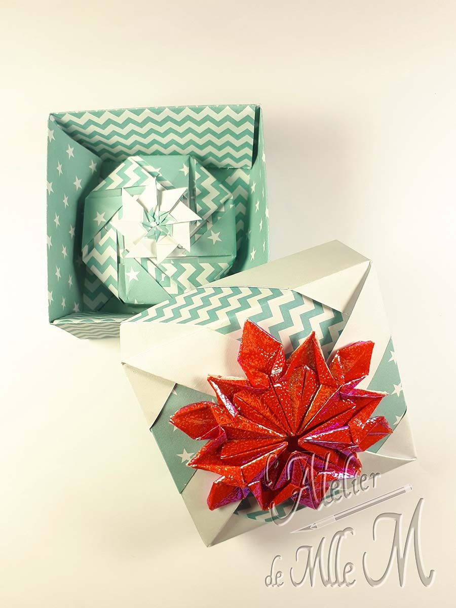Deux boîtes origamis s'emboitant, décorées par un flocon de neige origami iridescent.