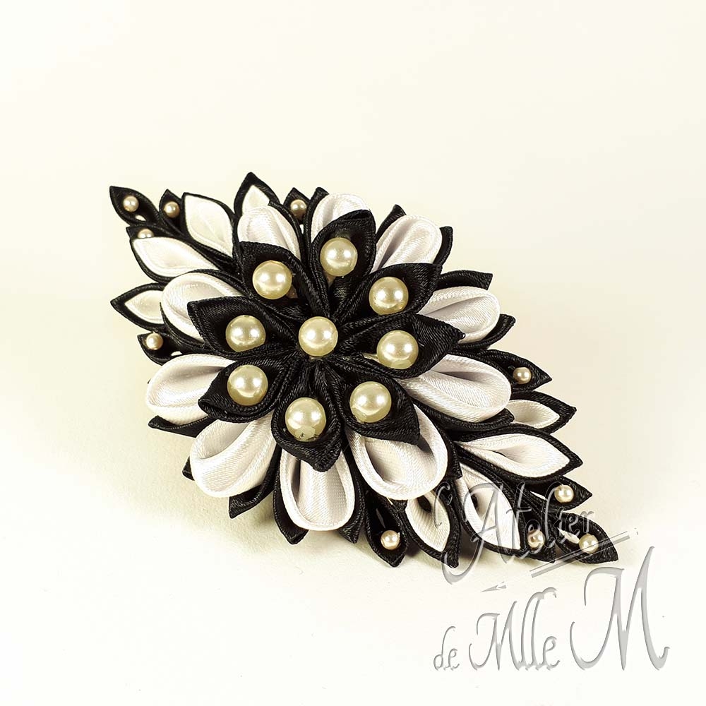 Une belle barrette noire & blanche rappelant une fleur, réalisée suivant l'art tsumami zaiku. Composition : Rubans de satin - Perles nacrées. Support de barrette en métal. Une revue complète à lire pour rétablir la vérité sur les Tsumami zaiku et les Kanzashi disponible sur https://www.latelierdemllem.com/verite-sur-tsumami-zaiku-kanzashi/